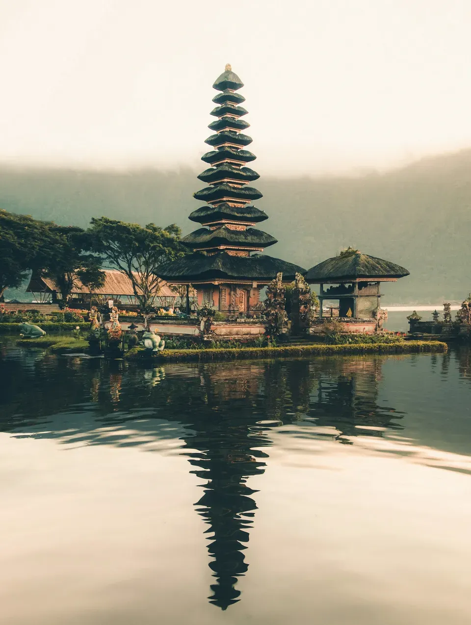 A Balinese temple beside a lake with mountains in the distance