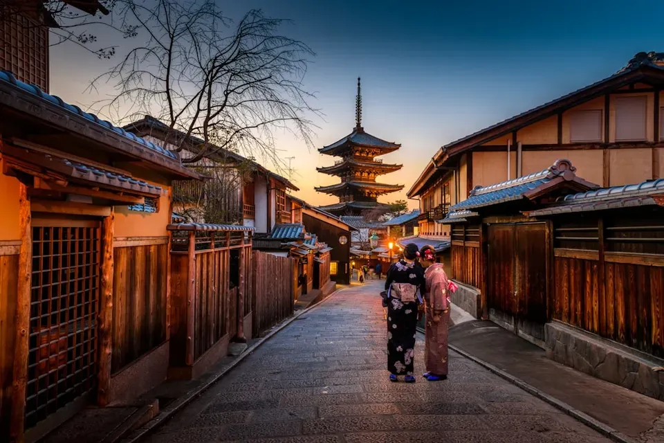 People walking along a traditional Kyoto street toward a pagoda